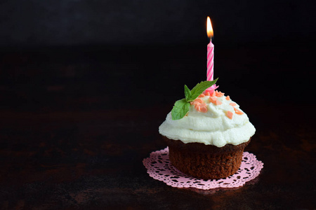 巧克力纸杯蛋糕，香草奶油和蜡烛。 生日快乐。 深色照片。