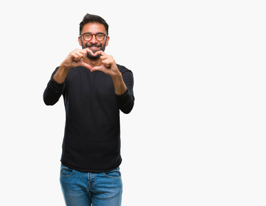 成年西班牙裔男子戴着眼镜在孤立的背景上微笑，在爱中显示心脏的象征和形状与手。 浪漫的概念。