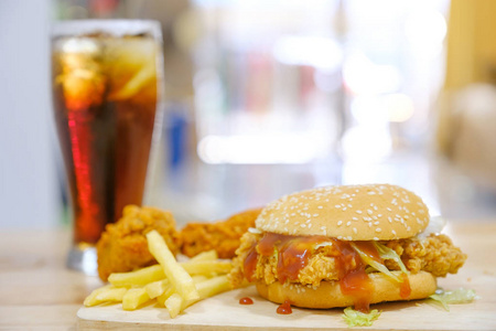 垃圾异味在温暖的光线下,鸡肉汉堡和可乐炸鸡.照片