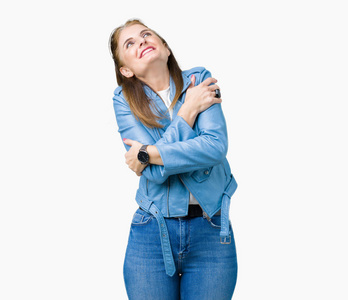 美丽的中年成熟的女人穿着时尚的皮夹克,在孤立的背景下拥抱自己,快乐