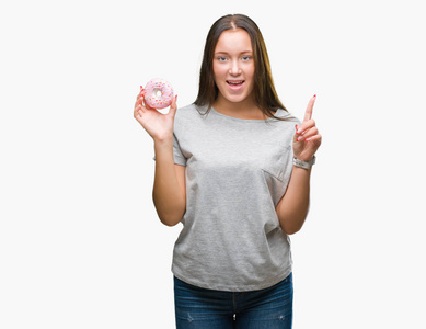 年轻的白种人女人吃甜面圈,在孤立的背景下惊讶惊讶地发现了一个想法