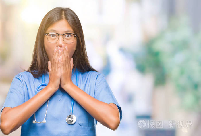 年轻的亚洲医生女人在孤立的背景下震惊地用手捂住嘴因为错误秘密概念