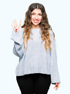 年轻漂亮的女人穿着冬天的毛衣，用手指第四，微笑着自信和快乐。