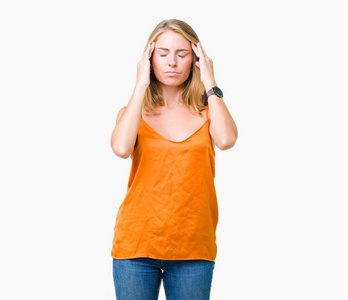 美丽的年轻女子穿着橙色衬衫，在孤立的背景上，手在头上疼痛，因为压力。 偏头痛。