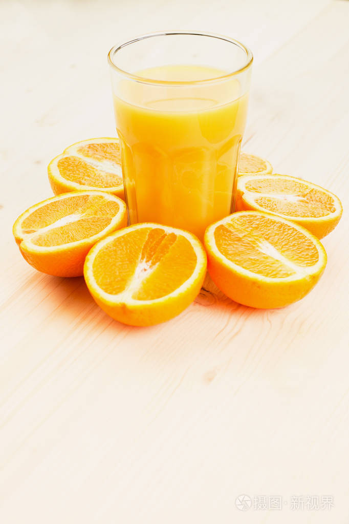 一杯新榨的橙汁,在木制背景上切成橙色的半片. 健康的生活方式概念.