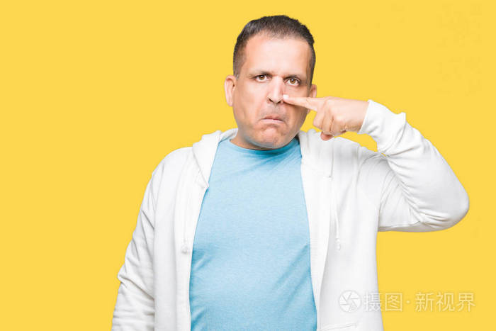 中年阿拉伯男子穿着运动衫背景与身体隔绝用手指着脸和鼻子微笑欢快