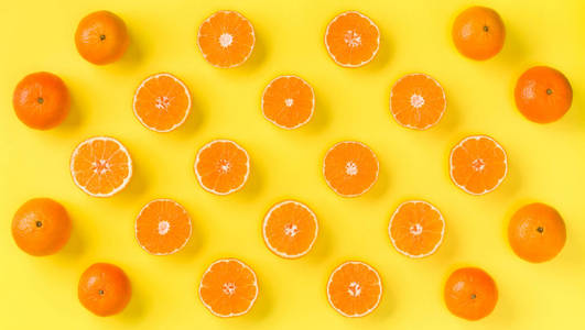 黄色背景下新鲜柑桔片的水果图案。 平躺顶部视图。 流行艺术设计创意暑期概念。 一半的柑橘在最小的风格。 橘子。