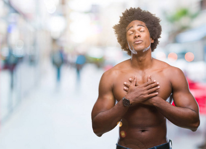 美国无衫男子显示在孤立的背景上微笑，双手放在胸部，闭着眼睛和感激的手势在脸上。 健康概念。