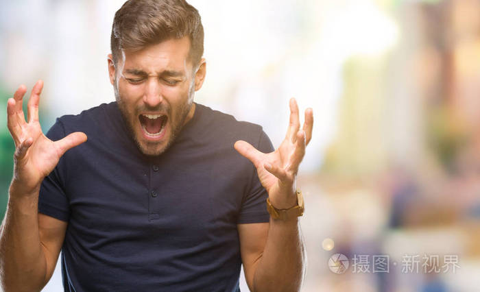 年轻的英俊男子在孤立的背景下庆祝疯狂和疯狂的成功，举起手臂和闭上眼睛尖叫兴奋。 赢家概念