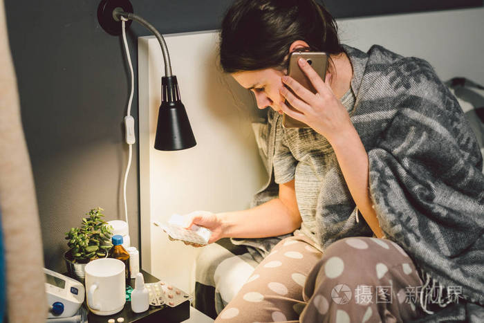 年轻的女人生病了,坐在床上,抱着喉咙悲伤的情绪. 喉咙痛的人吃药.