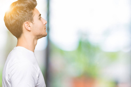 年轻英俊的男人穿着白色t恤,在孤立的背景下,看着侧面放松的轮廓,自然