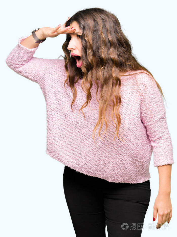 年轻漂亮的女人穿着粉红色的毛衣非常高兴和微笑用手捂住头看着远方