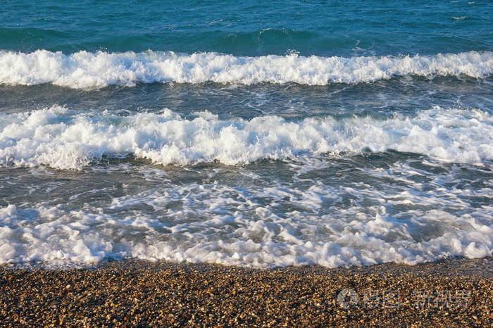 阳光明媚的风日，卵石海滩上白色波浪的水平线。 黑山亚得里亚海