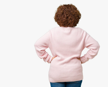 漂亮的中年老太太，穿着粉色毛衣，戴着太阳镜，背靠着孤立的背景，双手抱着身体向后看