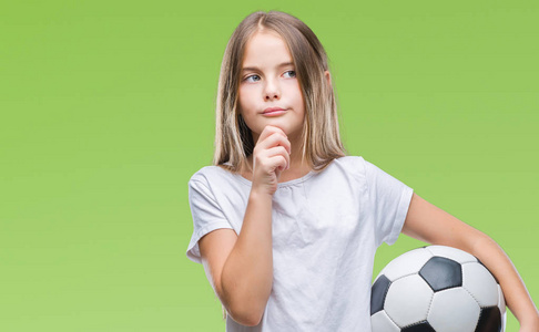 年轻漂亮的女孩抱着足球在孤立的背景下严肃的脸思考问题很困惑的想法