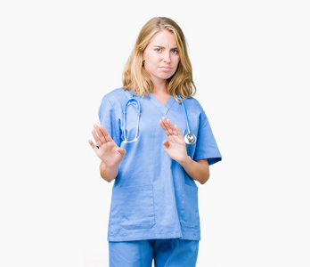 美丽的年轻医生女人穿着医疗制服，在孤立的背景下，厌恶的表情，不高兴和恐惧的做厌恶的脸，因为厌恶的反应。 举起双手。 令人讨厌的概