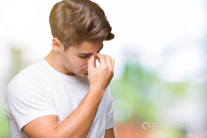 男人穿着白色t恤,在孤立的背景下疲惫地揉着鼻子和眼睛,感到疲劳和