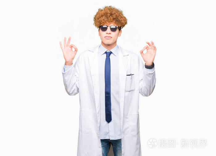 年轻英俊的科学家,穿着专业外套和太阳镜,放松和微笑,闭着眼睛,用手指