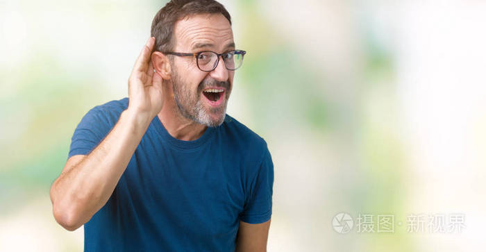 英俊的中年老人戴着眼镜在孤立的背景上微笑用手捂住耳朵听谣言或流言