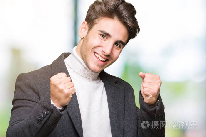 在孤立的背景下,非常高兴和兴奋地做着胜利者的手势,举起手臂,微笑着