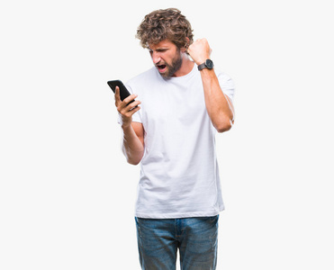 英俊的西班牙裔男子模型在孤立的背景下使用智能手机发送短信，愤怒和沮丧地大喊大叫，疯狂地举起手大喊大叫，愤怒的概念