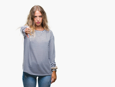 美丽的年轻金发女人穿着条纹毛衣，在孤立的背景上看起来不高兴和愤怒，表现出拒绝和消极的拇指向下的手势。 不好的表情。