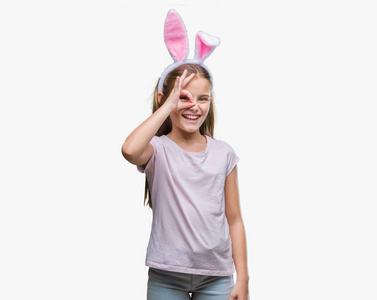 年轻漂亮的女孩穿着复活节兔子耳朵在孤立的背景上做着好的手势,用手