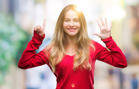 年轻漂亮的金发女人穿着红色毛衣，在孤立的背景上，用手指举着六号，微笑着自信和快乐。