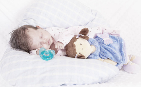 宝宝和娃娃睡觉. 奶嘴. 白色和蓝色背景.照片