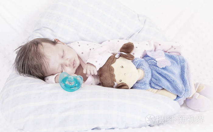 宝宝和娃娃睡觉. 奶嘴. 白色和蓝色背景.