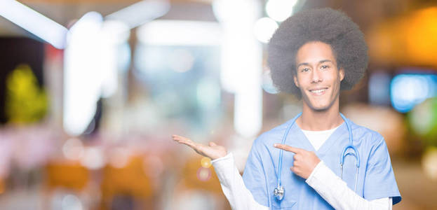 年轻的非裔美国医生，一个有非洲头发的男人惊讶地微笑着对着相机，用手和手指指点。