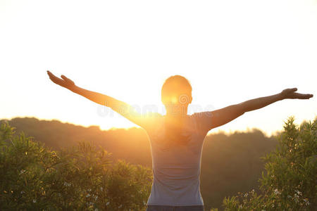 欢呼的女人在日出的山峰张开双臂照片