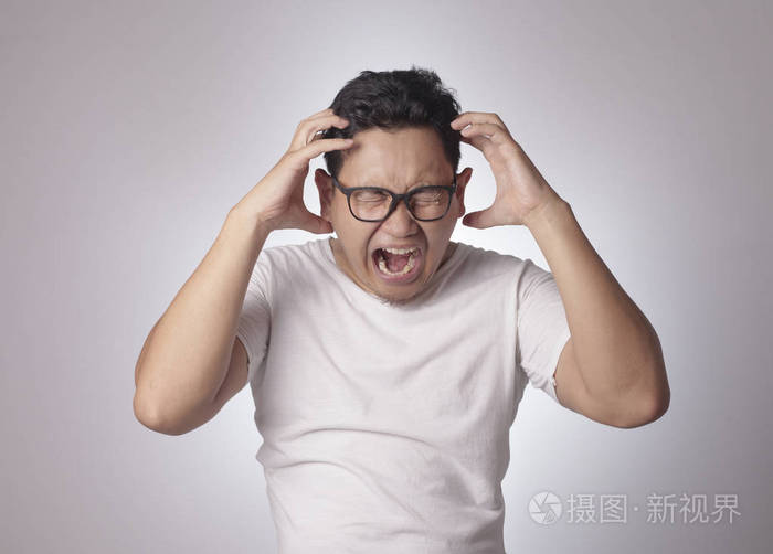 年轻的亚洲男人穿着白色衬衫因为愤怒而大喊大叫灰色背景抬起头和肩膀