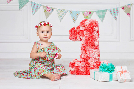 小快乐的蹒跚学步的女孩庆祝一岁生日。 可爱的女婴坐在大的1安夫盒子礼物
