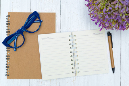 空白笔记本纸页和眼镜与笔和用品顶部视图。