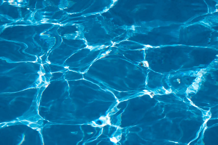 蓝色和明亮的波纹清洁水面在游泳池与太阳反射。
