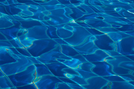 蓝色和明亮的波纹清洁水面在游泳池与太阳反射。