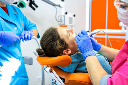 牙医和他的助手在牙科诊所治疗病人的牙齿