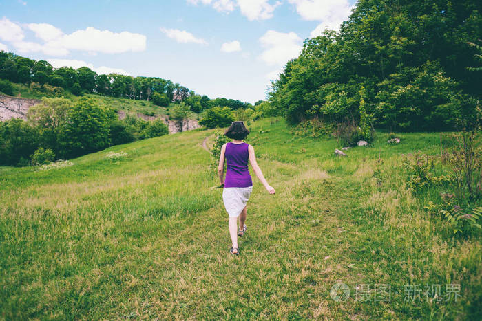 那个女孩拿着一束野花跑过田野女人在草地上收集花在一个阳光明媚的