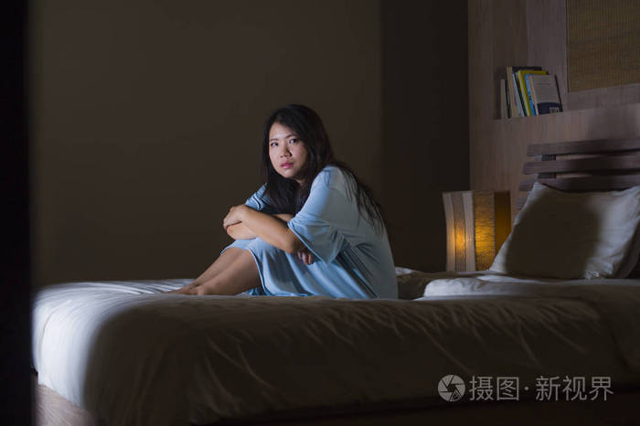 年轻美丽而悲伤的亚洲女性的戏剧性肖像她在床上绝望