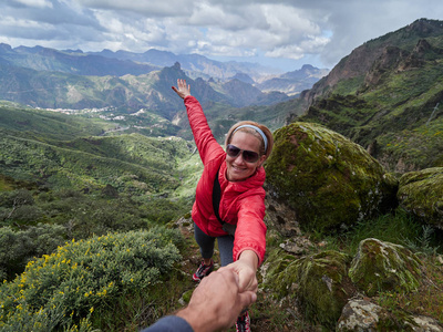 夏季高山地带的年轻女子游客男子帮助她攀登