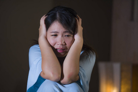 年轻美丽而悲伤的日本女人在床上绝望地哭泣，晚上醒来，遭受抑郁危机和失眠，感到痛苦和心碎