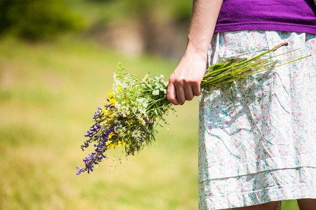 那个女孩捧着一束野花。 一个女人正在草地上摘花。 鲜花的礼物。 夏草。 在村子里休息。