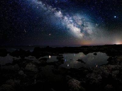 在岩石悬崖和海夜景观上令人叹为观止的充满活力的银河形象