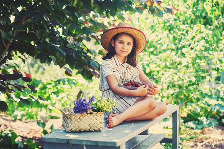 花园里有樱桃的女孩的肖像。 孩子拿着一盘新鲜的浆果