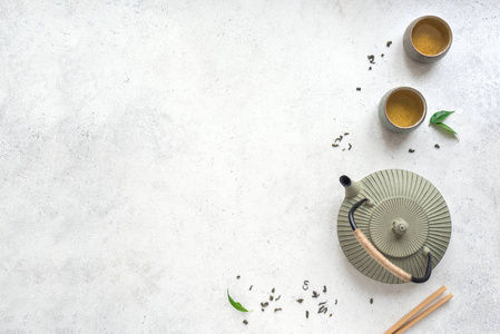 绿茶套铁茶壶和陶瓷茶杯与绿茶和叶子。 传统亚洲茶组合物在白色背景复制空间顶部视图。