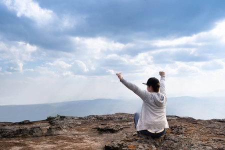 一个人坐在岩石山上，眺望美丽的自然景色和美丽的蓝天