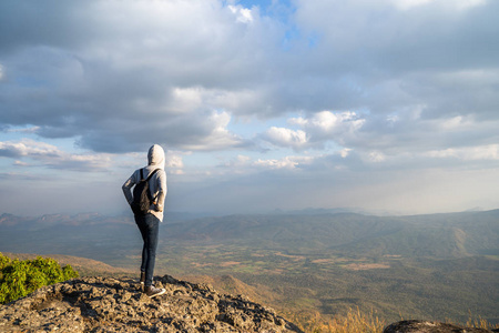 一位妇女站在岩石山上，眺望美丽的自然景色和美丽的蓝天