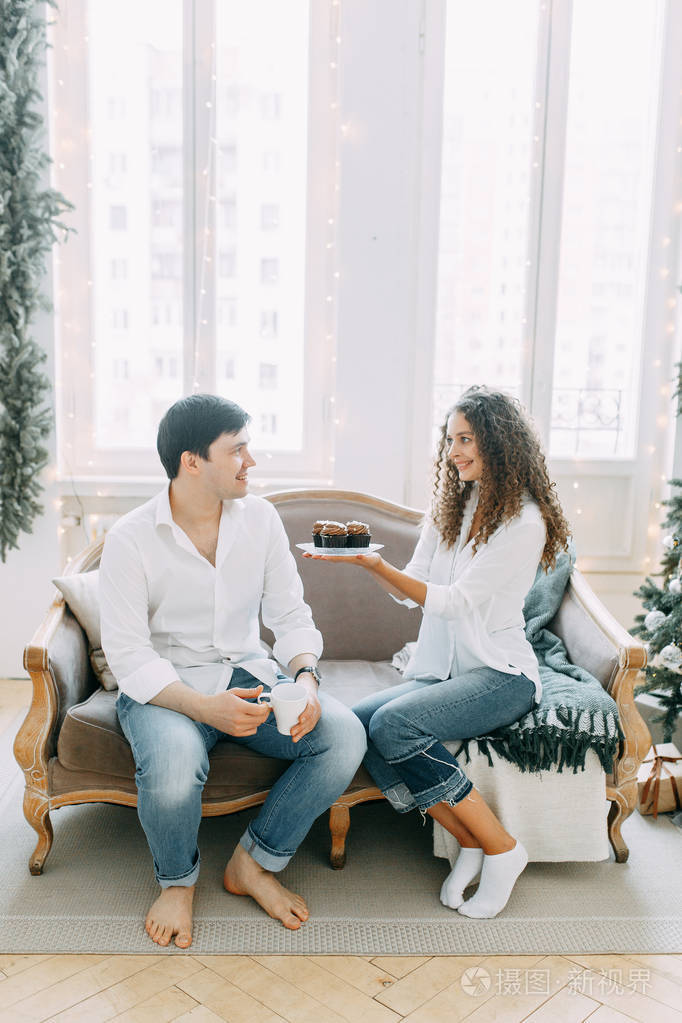 一对年轻夫妇躺在沙发上拥抱在一个明亮的室内工作室为新年拍摄照片