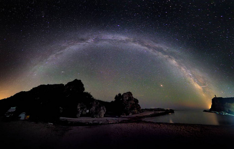 在岩石悬崖和海夜景观上令人叹为观止的充满活力的银河形象